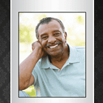 Smiling man in a light blue shirt, memorial photo for obituary remembrance.
